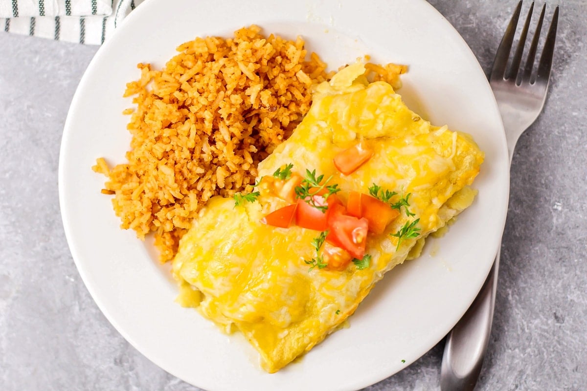 Close up image of our green chili chicken enchilada recipe on white plate.