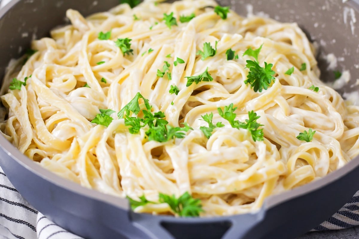 Fresh parsley sprinkled over easy Fettuccine Alfredo in skillet.