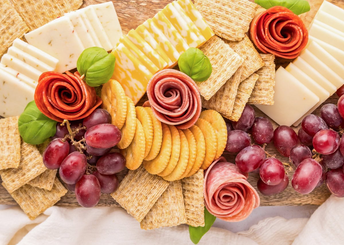 Pepperoni and salami roses rolled and placed on a charcuterie board.