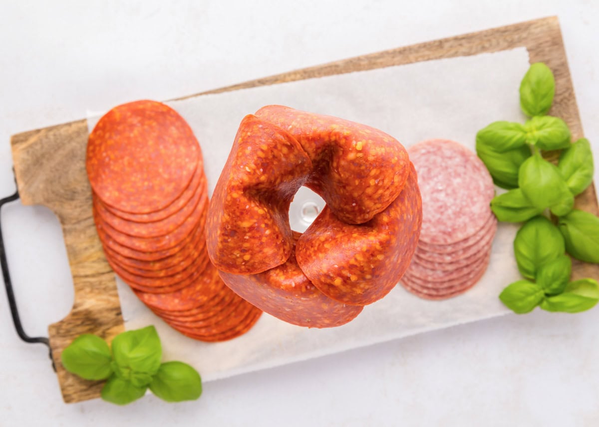 Layering pepperoni around the rim of a glass jar.