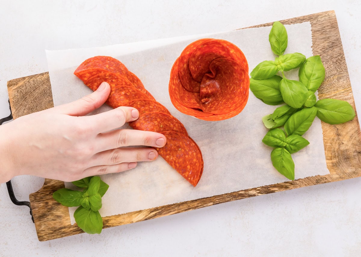 Layering, folding, and pushing pepperoni into a glass jar.