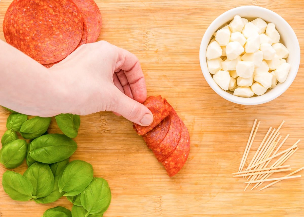 Rolling folded pepperoni in a roll.